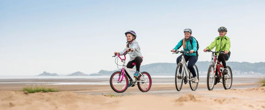 Family cycling on the beach in Swansea Bay